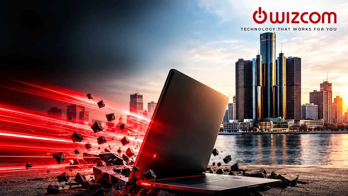 A laptop bursting apart in a streak of red light in front of the Detroit skyline, with the Wizcom logo